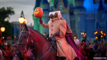 Person in costume riding horse with pumpkin lantern at Disney castle.